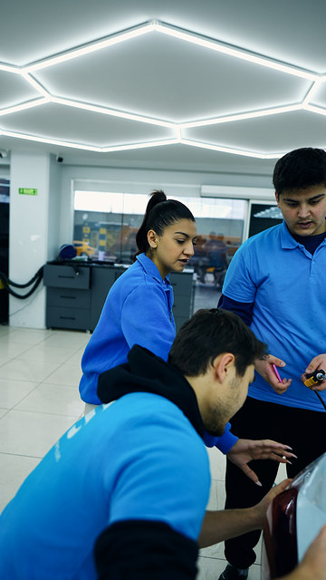 PPF kaplama eğitiminde stop lambası çevresine gelen film kenarını ısıyla şekillendirip kapatıyoruz; eğitmenimiz bunu araç üzerinde anlatıyor.