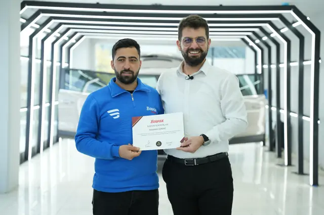 Belgede program adı “Car Detailing” olarak yazılı. Takdim, koridorun LED kemerlerinin önünde yapılıyor.

Aynı gün verilen belgelerde program adı değişiyor — herkes aynı eğitimi almıyor.