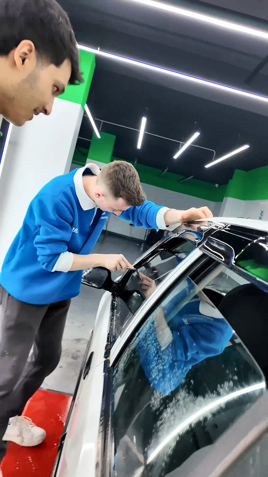 Kursiyerimiz kapı cam çerçevesi çevresindeki PPF kenarını ince bir aletle kapatıyor; Bowax Academy dersinden.