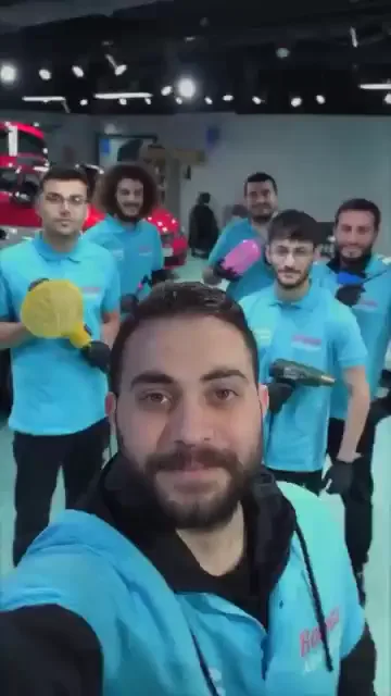 Kamerayı eline alan katılımcı, arkasındaki grubu tek karede topluyor; ellerinde polisaj pedleri ve makineleri var, herkes gülüyor. Devamında aynı kişi omzunda bir film rulosuyla kameraya doğru yürüyor. Yedi saniyelik kayıtta ne konuşma ne de ekran yazısı var.
