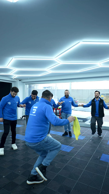 Bowax Academy'de eğitim arasında atölyede halay kurduk; kursiyerlerimiz ve ekibimiz araçların arasında birlikte oynuyor.