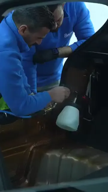 Aracın koltukları ve döşemesi alınmış, taban sacı tamamen açıkta duruyor. Eldivenli bir kişi pompalı bir kapla iç bölüme kimyasal veriyor, yanındaki kişi işlemi yakından izliyor.

Konuşma ve ekran yazısı olmadığı için kullanılan ürünün adı görülmüyor; kayda giren şey, temizliğin döşeme sökülerek yapıldığı.