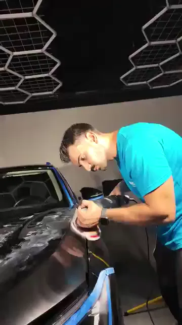 Koyu boyada her iz göze battığı için panel, ışığın doğrudan vurduğu açıda çalışılıyor. Cam fitilleri ve panel birleşimleri bantla kapatılmış; ped bu kenarlara yüklenmeden gezdiriliyor. Çalışma arasında yüzeye eğilip alçak açıdan bakılıyor — koyu renkte kontrol, makinenin durduğu an başlıyor.