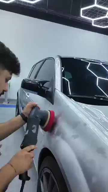 Makine gövdesinden kavranıp panele paralel tutuluyor; kapı ve arka çamurluk boyunca üst üste binen geçişlerle ilerleniyor. Tavandaki altıgen aydınlatma doğrudan panele düşürülüyor, böylece yüzeydeki izler çalışma sırasında görülebiliyor. Polisajda sonucu ilerleme hızından çok pedin yüzeye oturuşu belirler.