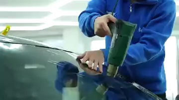 Aydınlık bir atölyede bir kişi ısı tabancasını ön camın üst kenarı boyunca soldan sağa gezdiriyor, boştaki eliyle filmi düzeltiyor. Cama serilen film ısındıkça kenarlardan içeri doğru toplanıyor. Tavandaki aydınlatma cam ve kaput üzerinde boydan boya yansıyor.