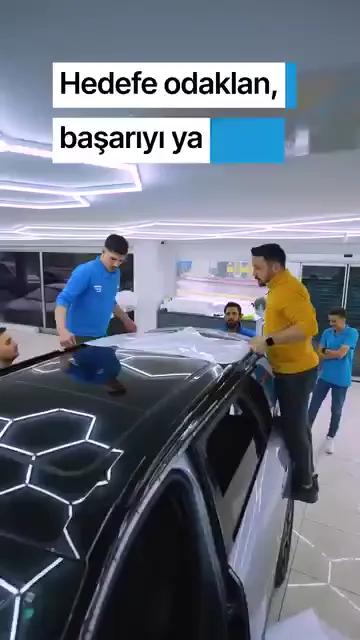 Ekranda “Hedefe odaklan, başarıyı yakala!” yazısı dururken kareler film uygulamasını gösteriyor: koyu renkli aracın tavanına serilen film ragle ile bastırılıyor, gri aracın kaputunda iki kişi birlikte çalışıyor. Aralarda kaputu açılmış bir aracın başında grup halinde inceleme, turuncu bir aracın tekerlek kemerinde ise kesilmiş film parçasının yerleştirilmesi var. Kayıtta konuşma yok.