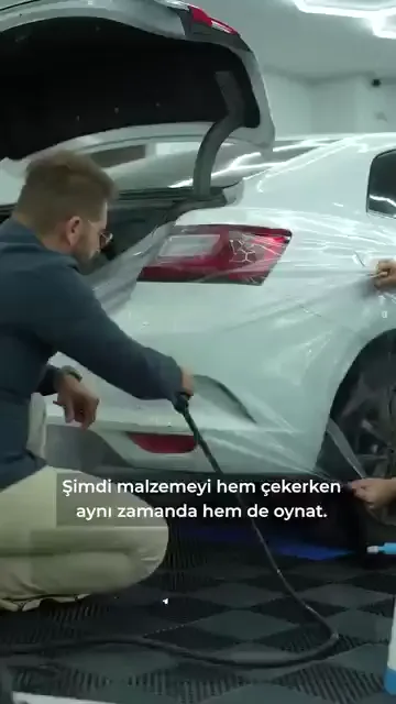 Malzemeyi yalnızca çekmek yetmiyor; çekerken aynı anda oynatmak gerekiyor. Aşağı-yukarı hareketle film kıvrımını alıyor.

Sıra da önemli: önce gerginlikten başlanıyor, malzeme yönüne doğru giydiriliyor, en son altındaki su çekiliyor.

Yön sorusunun cevabı parçanın kendisinde. Tampon nereye, kaput nereye, bagaj nereye — "Yön nereyse sen orası." Ters yöne çekilen film bir süre sonra kalkıyor.

Doğru giydirildiğinde malzeme serbest bırakılsa bile yerine dönüyor; videoda bu canlı olarak gösteriliyor.