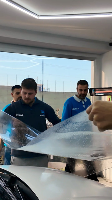 Eğitmenimiz, kaputa PPF uygulanırken filmi gereğinden fazla çekmenin kenarda sorun bıraktığını, çekilen filme yol verilmesi gerektiğini anlatıyor.