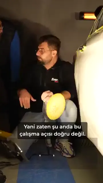 Tartışma net bir itirazla başlıyor: "Yani zaten şu anda bu çalışma açısı doğru değil." Liftsiz çalıştığını söyleyen kişiye kapının alt bölgesindeki çizik gösteriliyor.

Sorun tek bir araç değil, tekrarı. "Her gün yapacaksın bu arabayı" cümlesi işin özeti: bir seferlik zorlanmak mümkün, bunu günlük düzen hâline getirmek başka bir şey.

Yere yatarak çalışıldığında hem görüş açısı hem makinenin çalışma açısı kapanıyor; çiziğin gidip gitmediğini göremediğiniz bir yerde çalışmış olmuyorsunuz.

"Bu iş kişiyle bitiyor" derken kastedilen de bu: yöntem kişinin bedenine bağlıysa, o kişi olmadığında iş de duruyor.