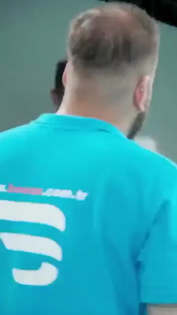 Ders beyaz tahtanın başında başlıyor; eğitmen elindeki pedi göstererek anlatıyor, katılımcılar çevresinde duruyor. Ardından grup, kenarları bantla maskelenmiş siyah aracın etrafına dağılıyor. Kareler boyunca eldivenli eller döner pedli makineyi panel üzerinde gezdiriyor, bir kişi de arkadan izliyor. Kayıtta konuşma yok; görünen tek şey makine, ped ve maskeleme bandı.