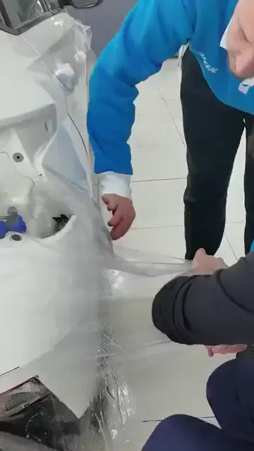 Şeffaf film bir aracın yan yüzeyine oturtuluyor; karelerde ragle ve iki kişilik bir tutuş görünüyor.

Uyarı hep aynı yere dönüyor: malzeme bırakılmayacak, gevşetilmeyecek. Bir anlık gevşeme, o ana kadar yapılan çalışmayı boşa çıkarıyor.

Karşılaştırma da yapılıyor; aynı noktadan çekildiğinde malzemenin ne kadar daha fazla geldiği gösteriliyor. Hedef net: malzemeyi hiçbir yerinde pot bırakmadan yerine oturtmak.
