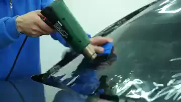 Yakın planda sağ el ısı tabancasını, sol el mavi ragleyi tutuyor ve ikisi aynı bölgede birlikte ilerliyor. Isıtılan film gevşerken ragle onu hemen cama doğru bastırıyor, kırışıklar kare kare azalıyor. Isı tek başına yetmiyor; gevşeyen film aynı anda bastırılmazsa yeniden kabarıyor.